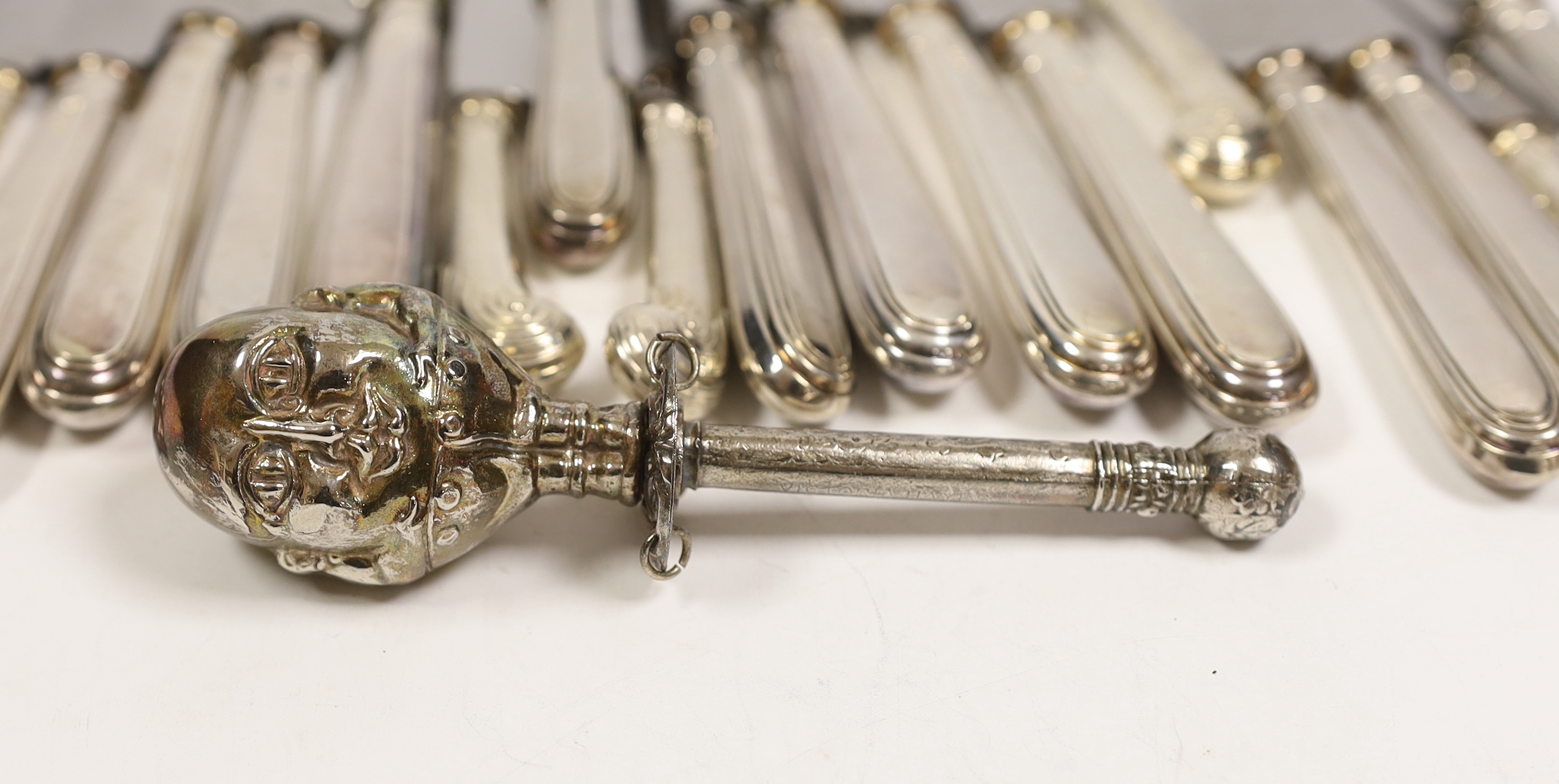 A set of six modern silver handled dessert knives and six table knives, Garrard & Co Sheffield, 1974, a set of six silver pistol handled tea knives and a silver plated 'Humpty Dumpty' child's rattle(a.f.).